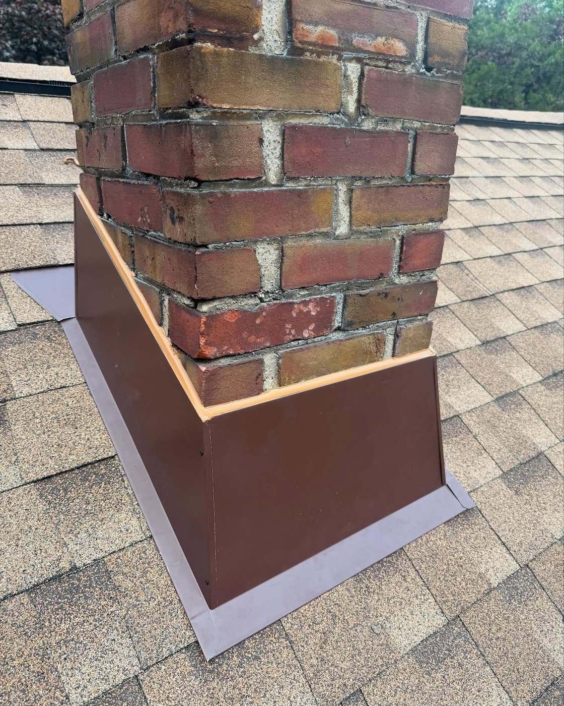Brick chimney on a Levittown, PA roof with new aluminum trim wrapped around its base