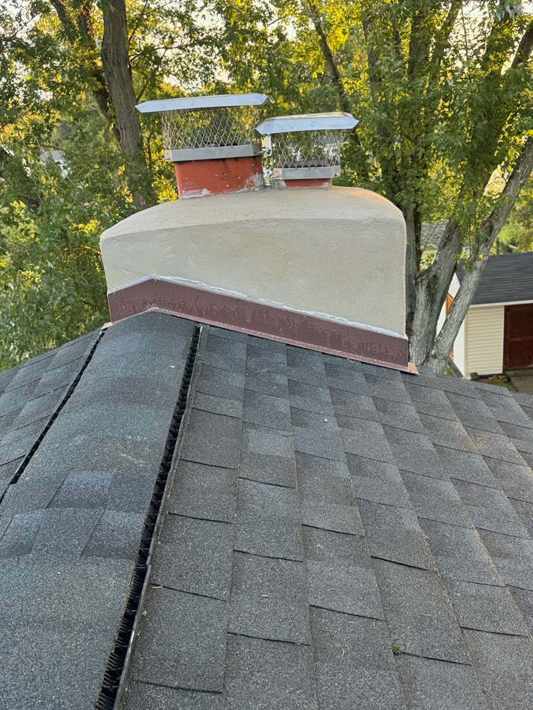 Concrete chimney crown with two stainless steel flue caps, seen from the roof