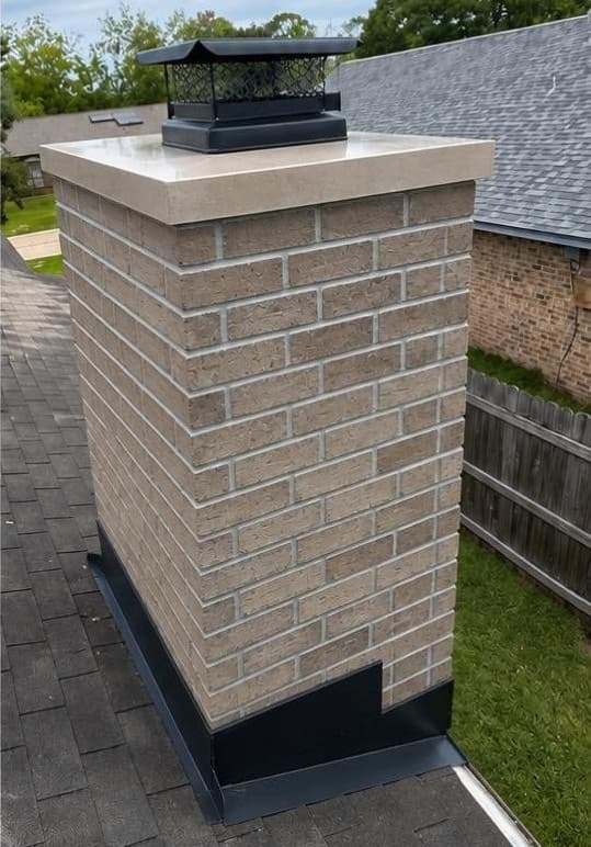 Rebuilt tan brick chimney with a new crown and a black cap on a Doylestown, PA home