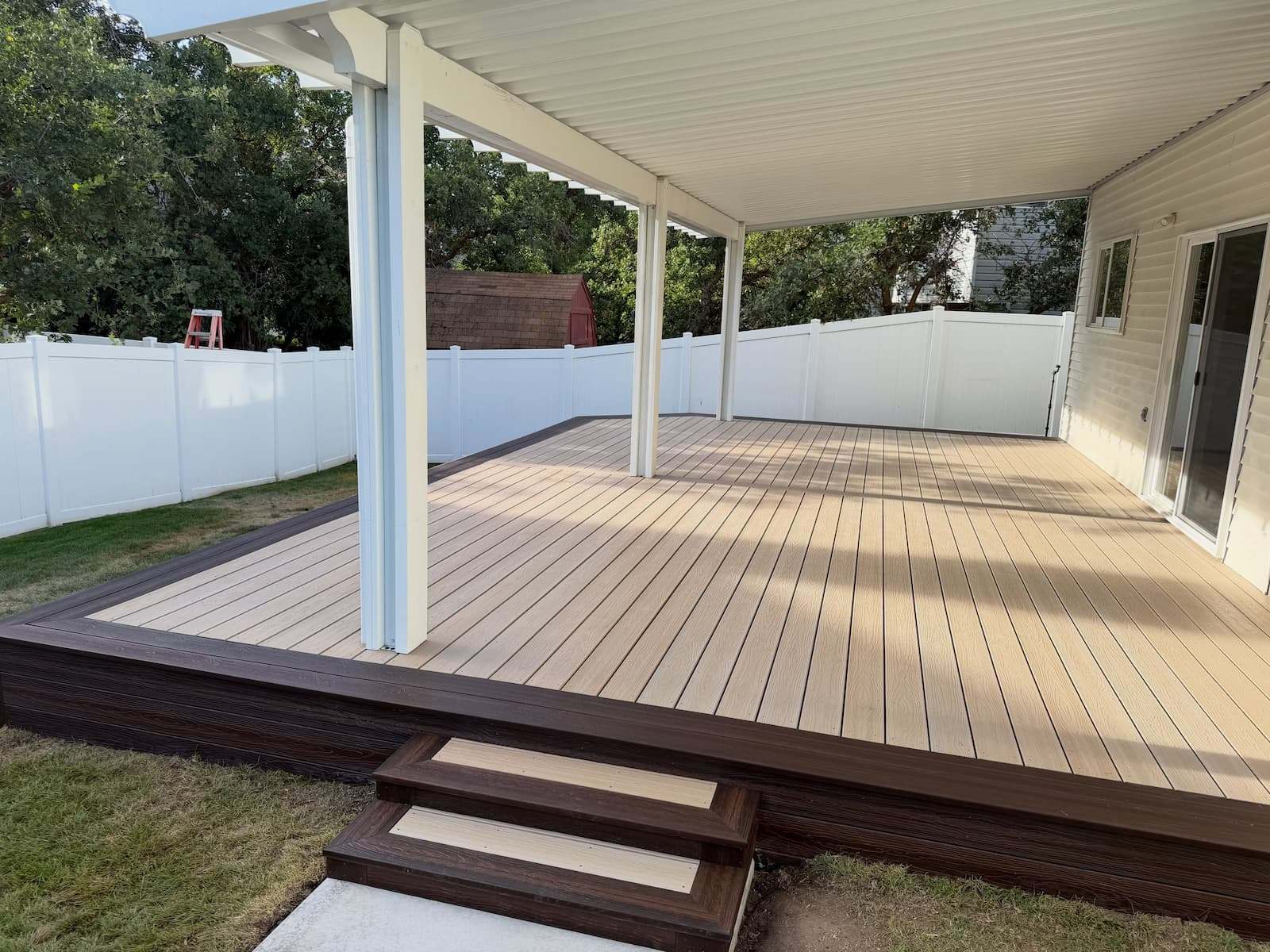 New composite deck under a covered patio roof at a Wayne, PA home, with steps down to the yard