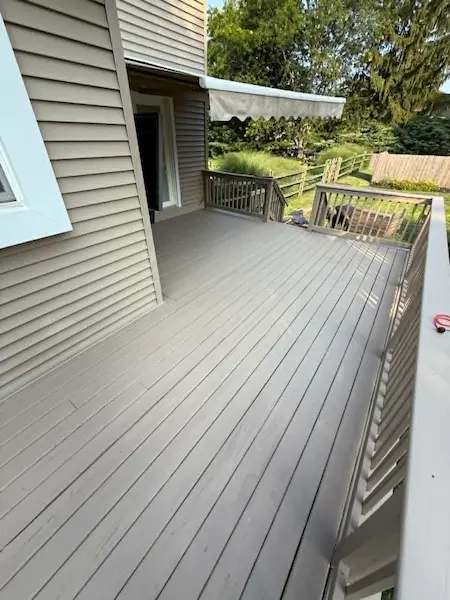 Long deck along the side of a house with new grey boards and railings